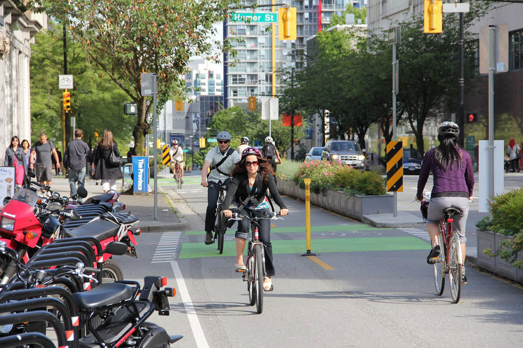 Some bicyclists are riding in the bicycle lanes which are separated by lane separators