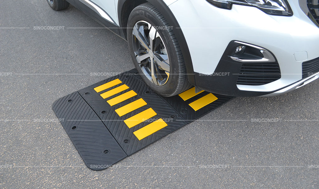 A black speed hump with a car on it.