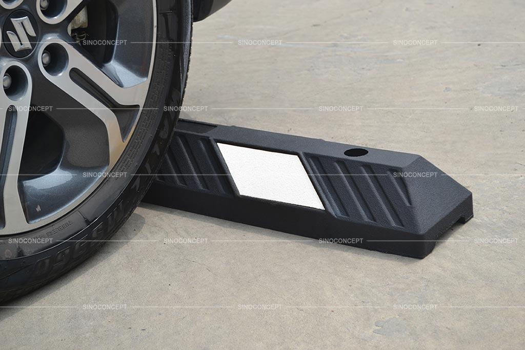 A black rubber wheel stopper pasted with white reflective films for parking safety purpose