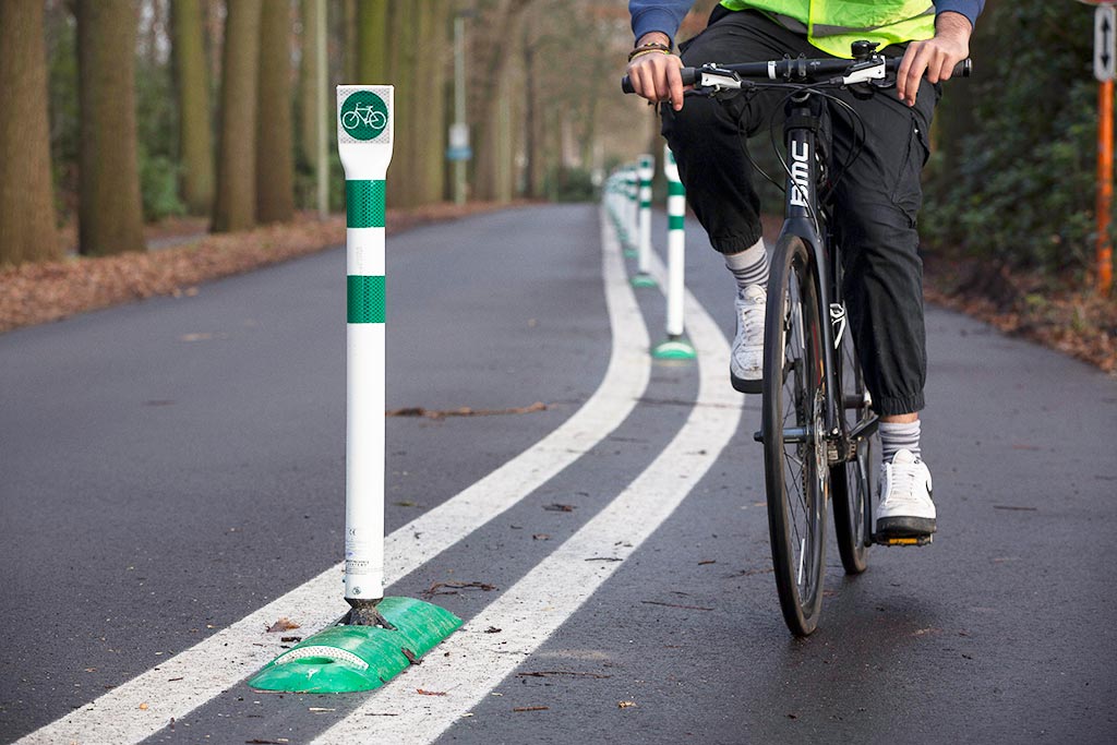 Green cycle lane dividers with white and green signposts inserted on the base to divide cycle lanes for cyclists