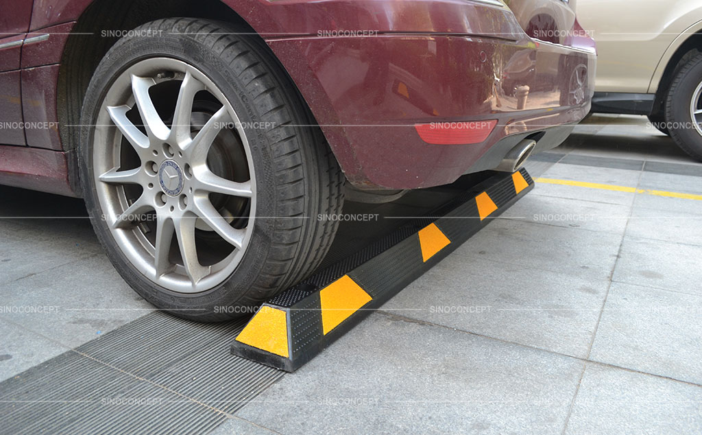 A long parking bumper made of black rubber and pasted with yellow reflective tapes to stop wheels