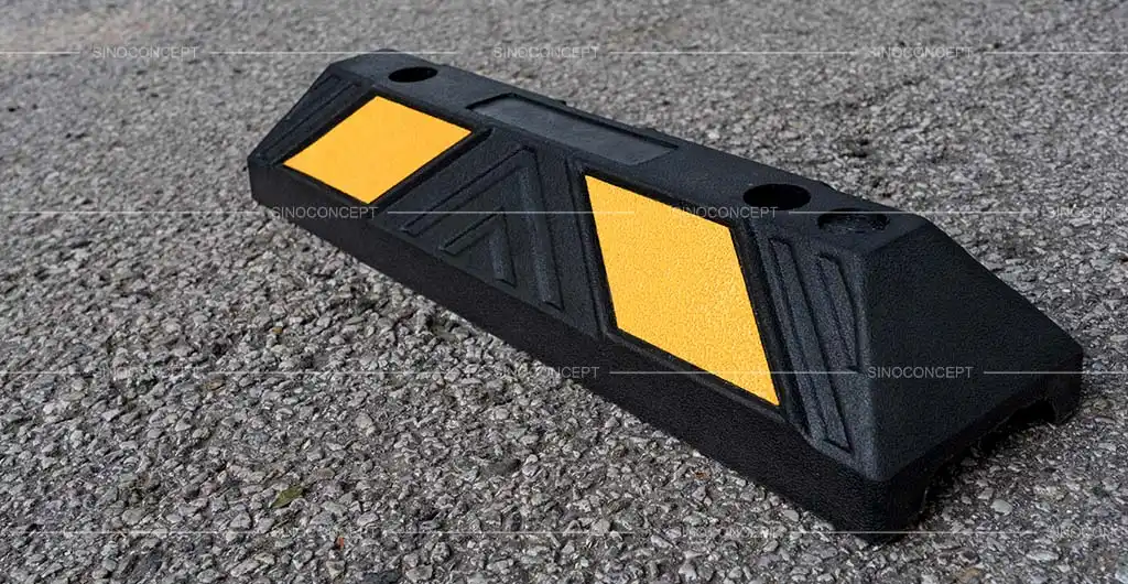 A black rubber parking kerb with yellow reflective films used for car park management.