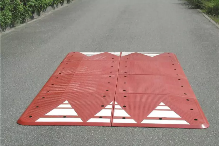 A red rubber Europe style speed cushion is mounted on the road as a speed management tool.
