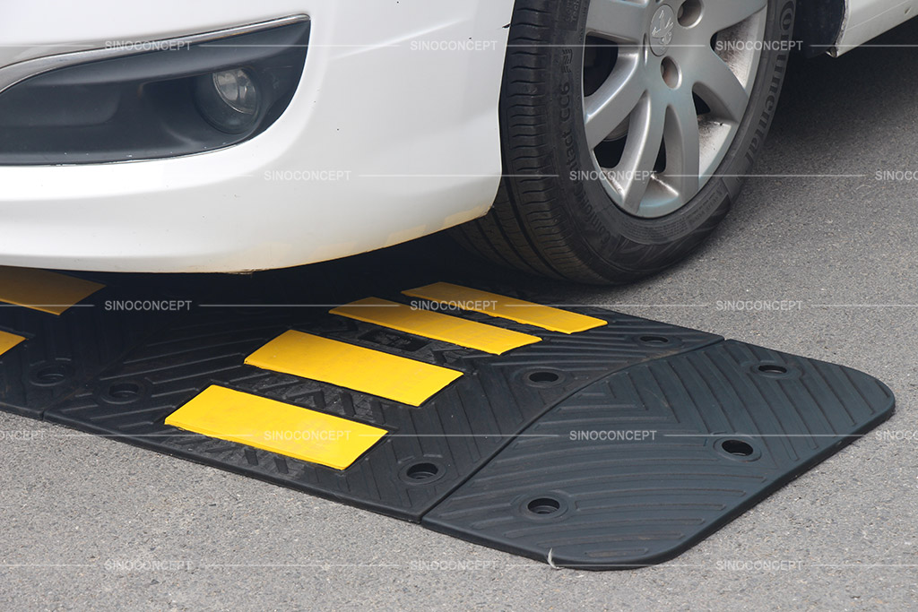 A road hump made of black recycled rubber with yellow reflective films used to reduce vehicle speed