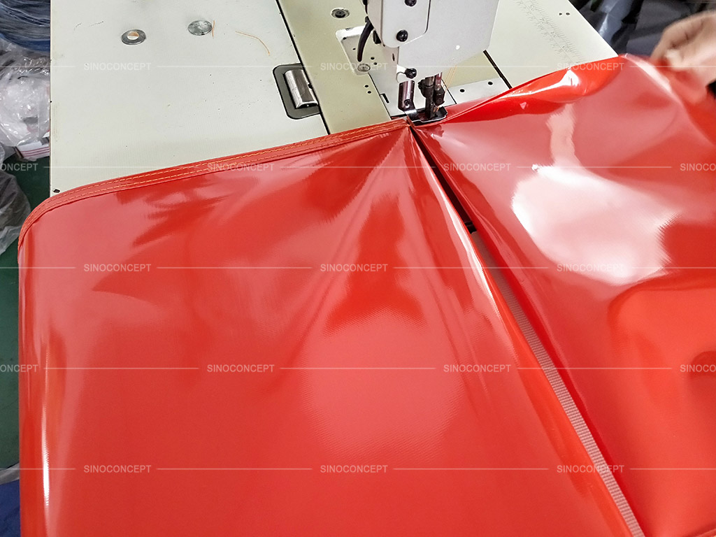 A worker is sewing the PVC materials together to make an empty sandbag