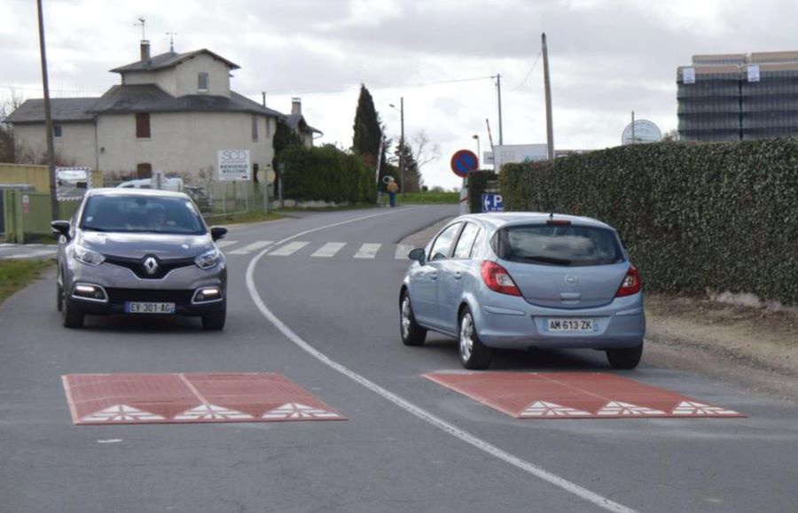 Two red rubber speed cushions on the road for traffic-calming management.