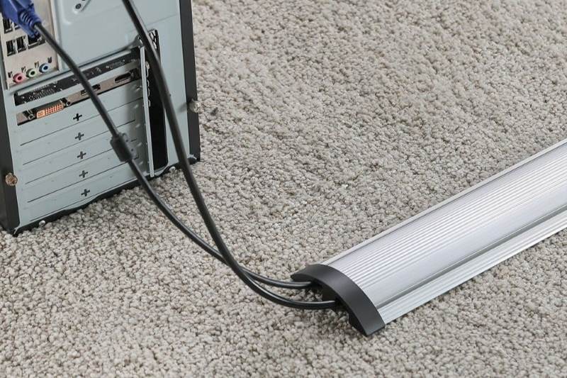 A silver floor cable cover hides and protects wires and reduces tripping hazards.