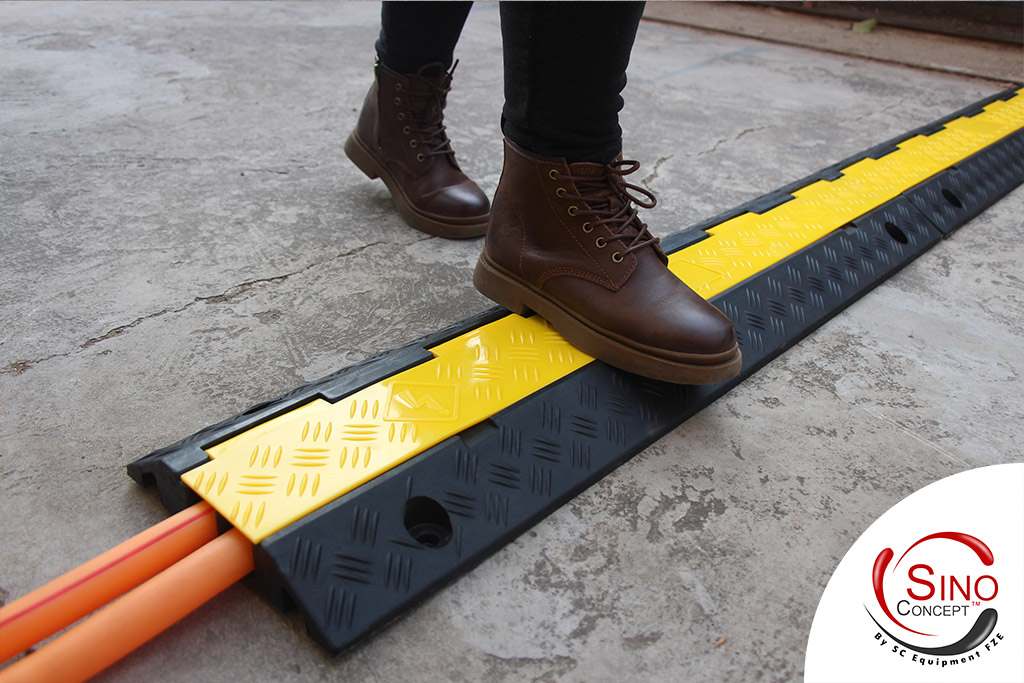 A black and yellow cable ramp made of rubber keeps people safe since it reduces tripping hazards and creates a secure environment.
