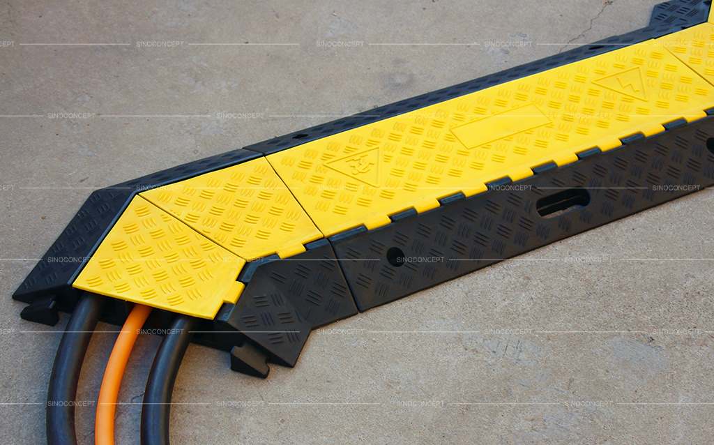 A 3-channel black and yellow cable ramp made of rubber on the ground.