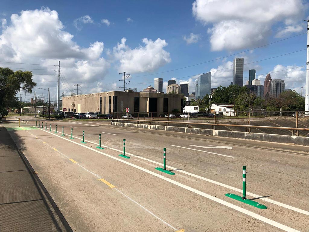 Green bike lane dividers with green posts fixed onto them to separate cycle lanes from motor vehicle lanes