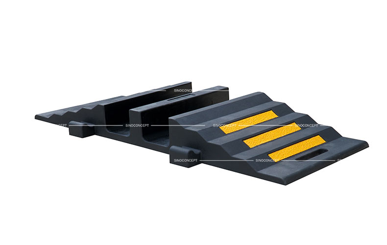 A black rubber hose protector ramp with yellow reflective films to protect hoses or cables.