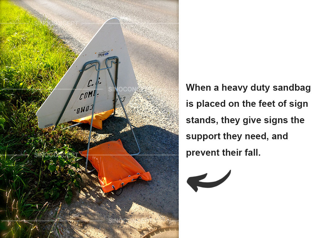 An orange sand bag used to stabilize a triangle traffic sign at the roadside