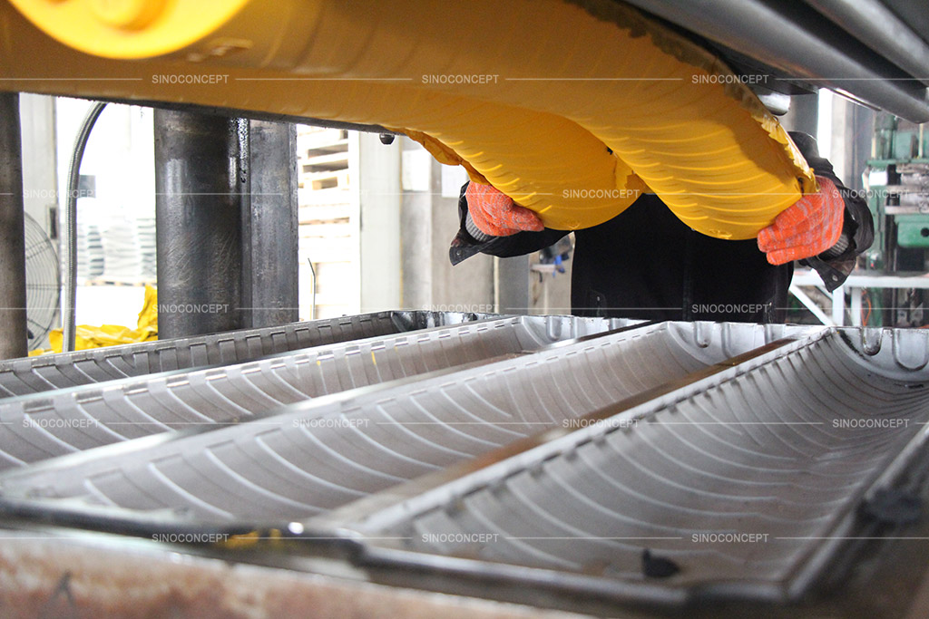 A worker is manufacturing a yellow rubber cable ramp