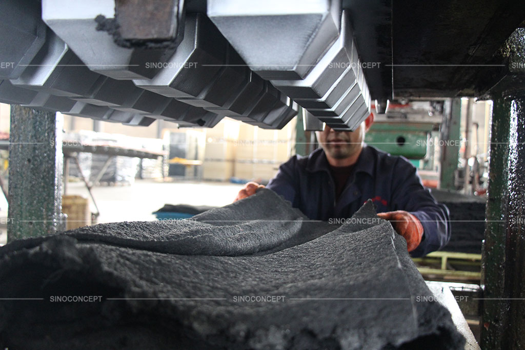 A worker is setting rubber material in the mould for manufacturing wheel stoppers.
