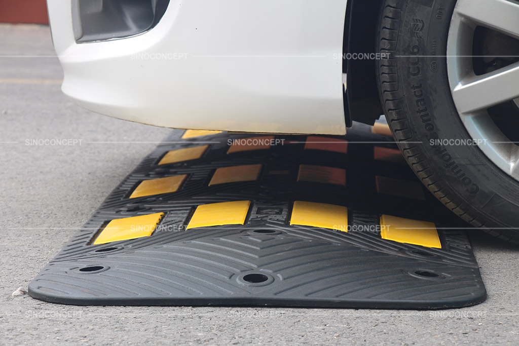 Traffic calming hump made of recycled rubber, coloured in black and pasted with yellow reflective tapes