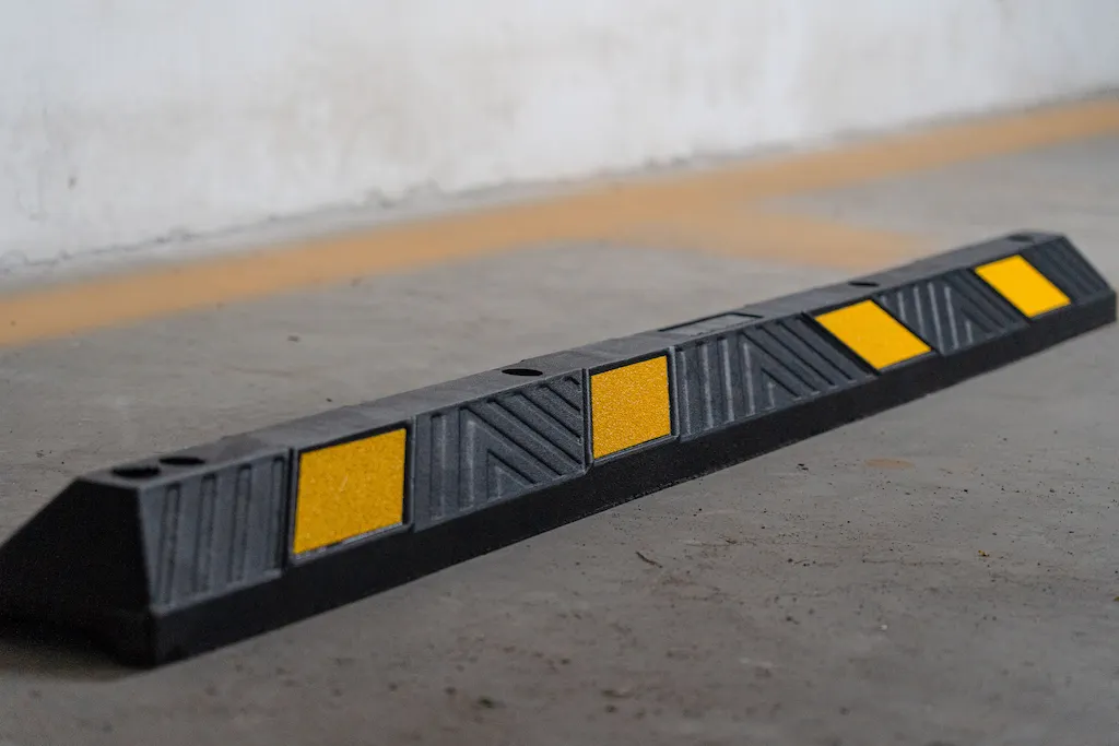 A black rubber wheel stop with yellow glass bead reflective films.