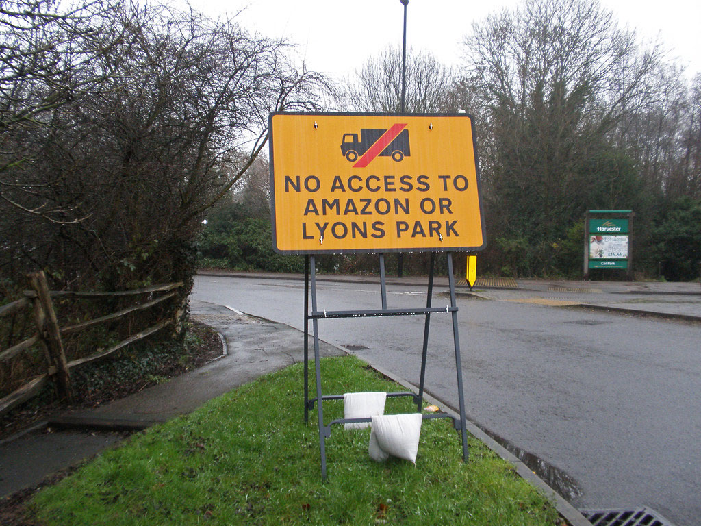 White sandbags are used to hold down a big traffic warning sign on the roadside.