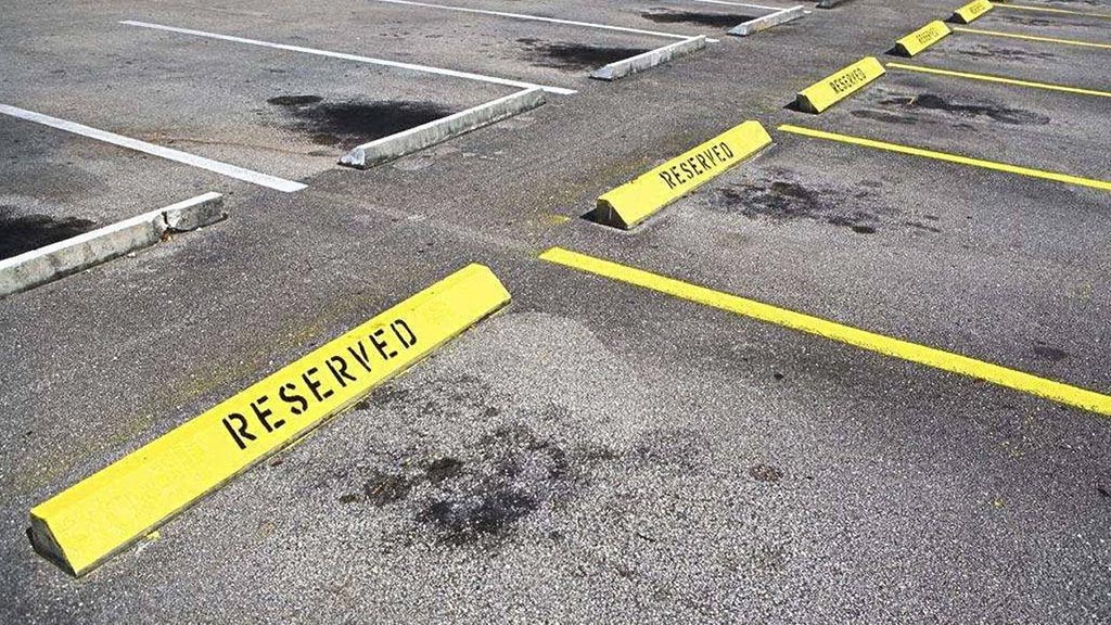 Yellow parking wheel stops with "reserved" warning words on them installed on the floor