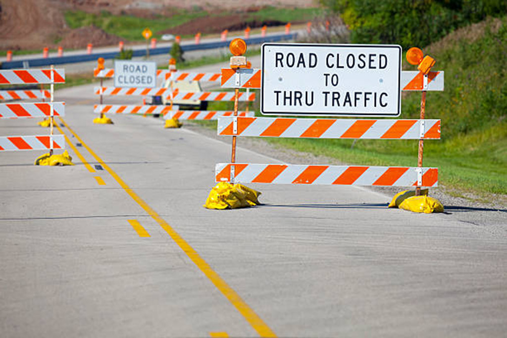 Yellow sandbag sacks used to hold down construction warning signs on the road