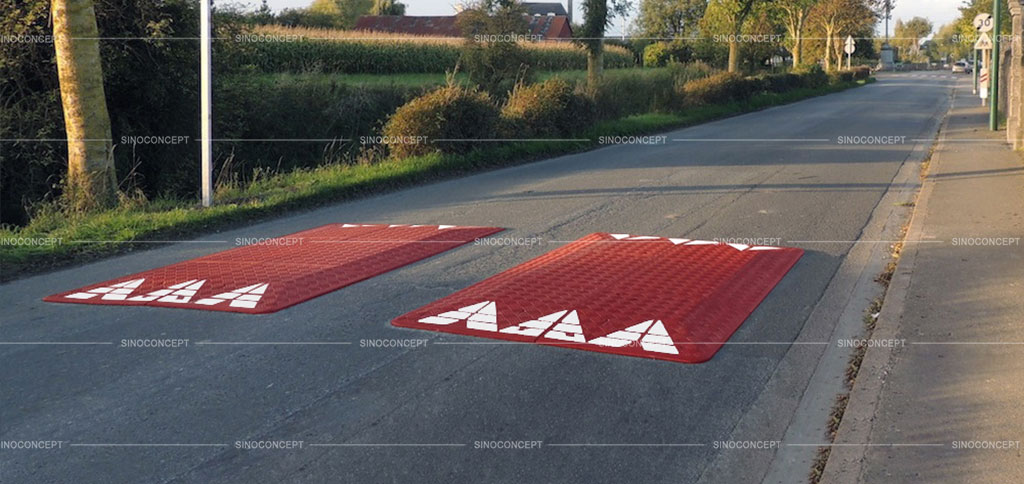Two red speed cushions are placed on the road to reduce vehicles' speed