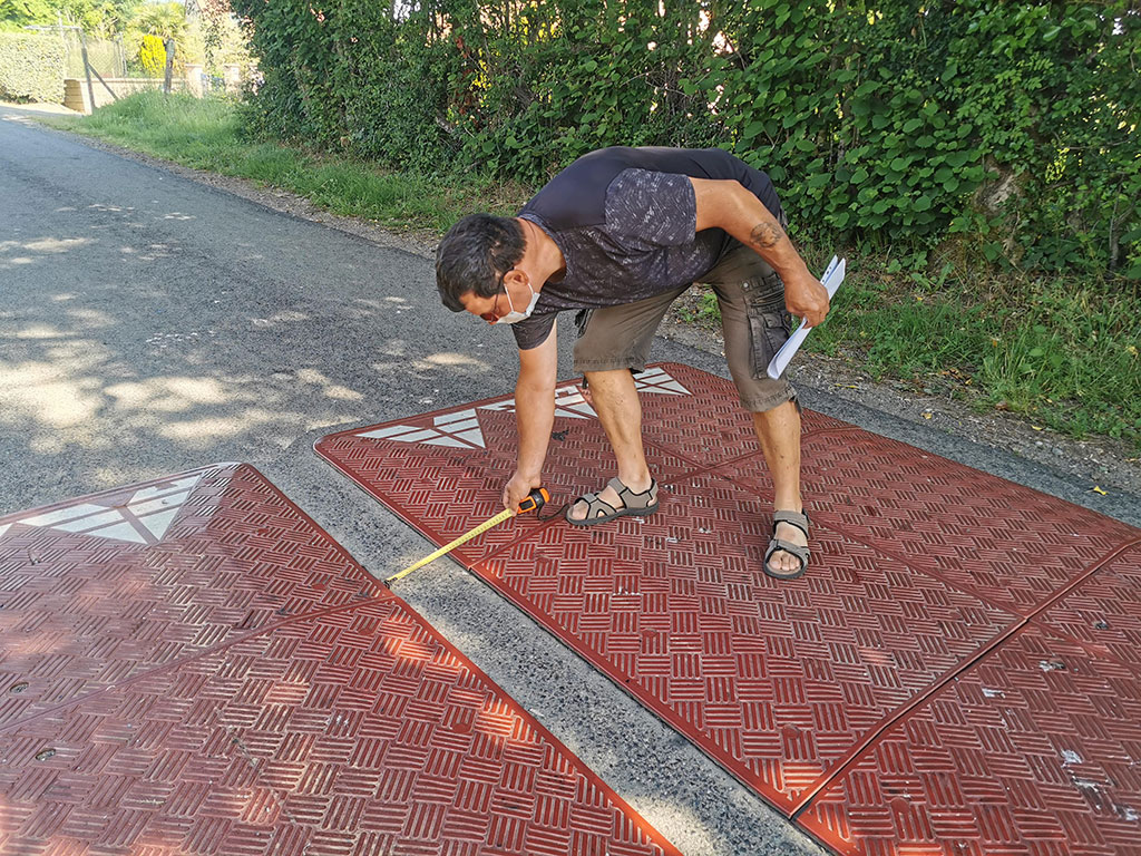A man is measuring the space between two speed cushions