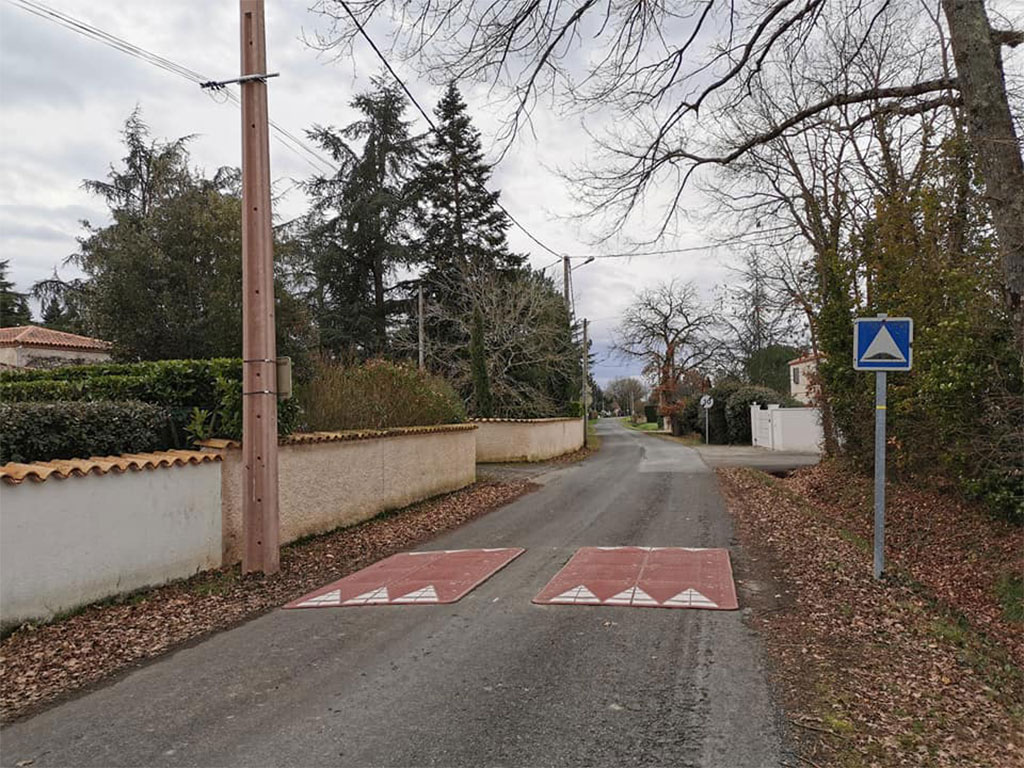 Two red speed cushions also called speed tables are placed on the road in a village for residents' safety