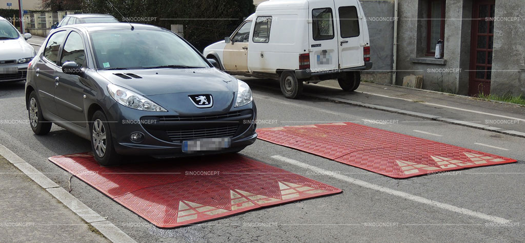 Red speed cushions with white arrow films, fixed on the road to reduce traffic speed