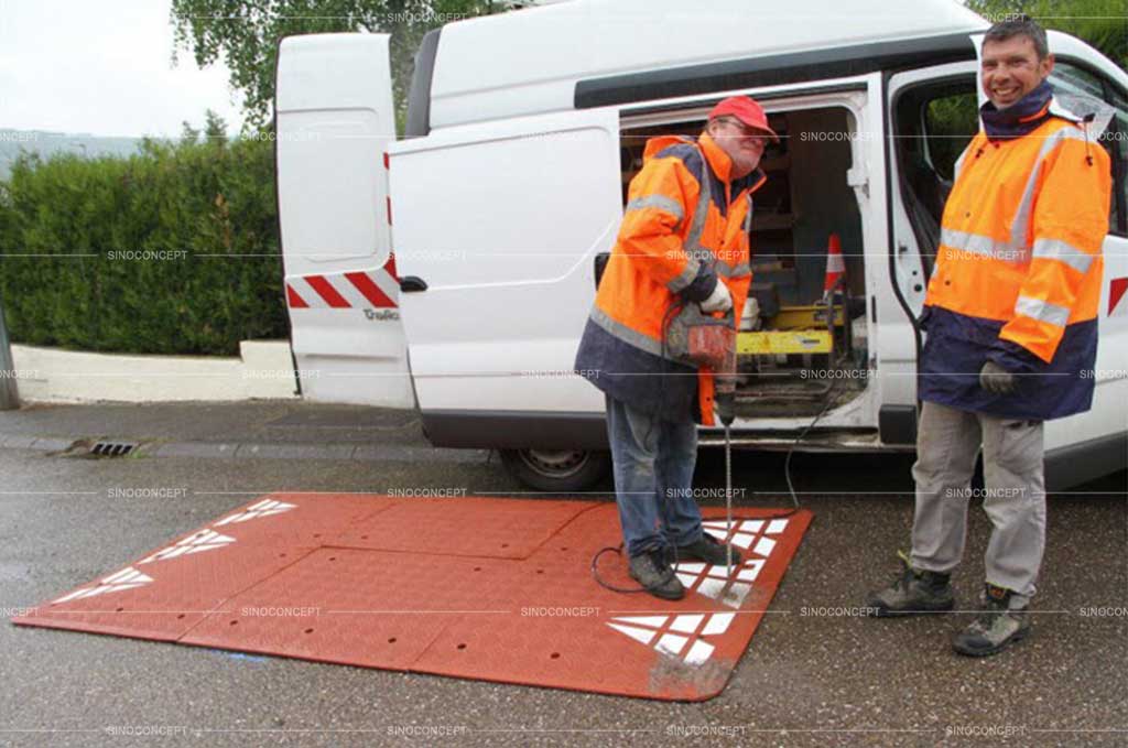 Two workers are installing a rubber speed cushion on the road