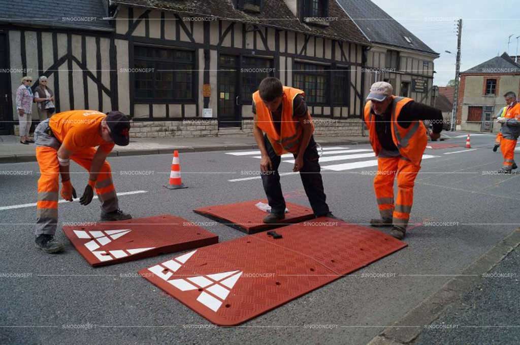 Some workers are installing a rubber speed cushion that is made of four parts