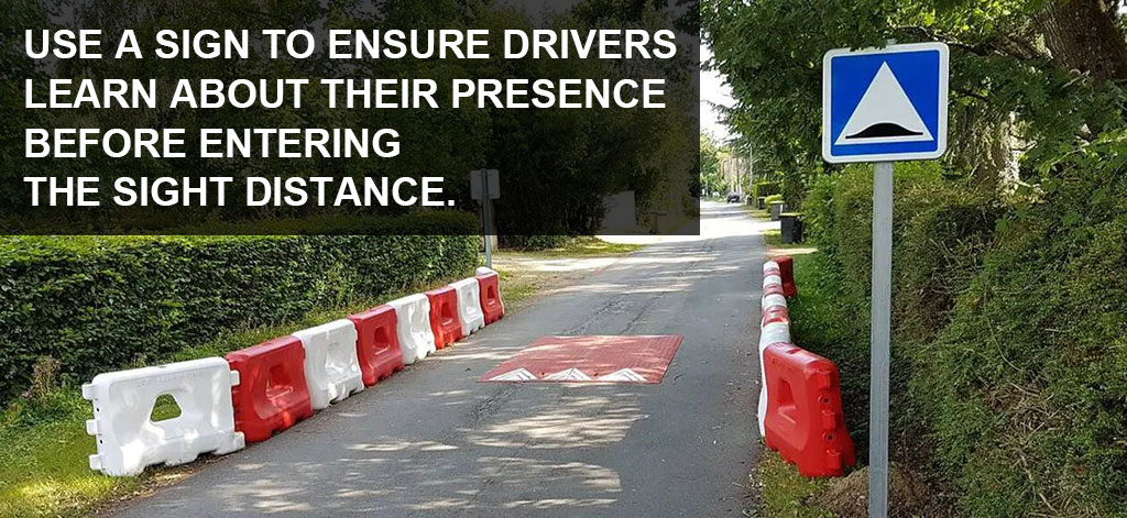 A sign post is installed before a speed cushion to remind drivers of the device