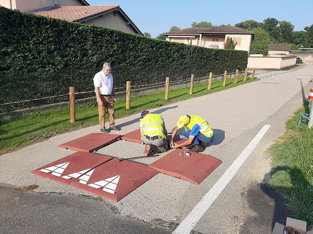 Two workers are installing a rubber speed cushion on a road in the neighbourhood