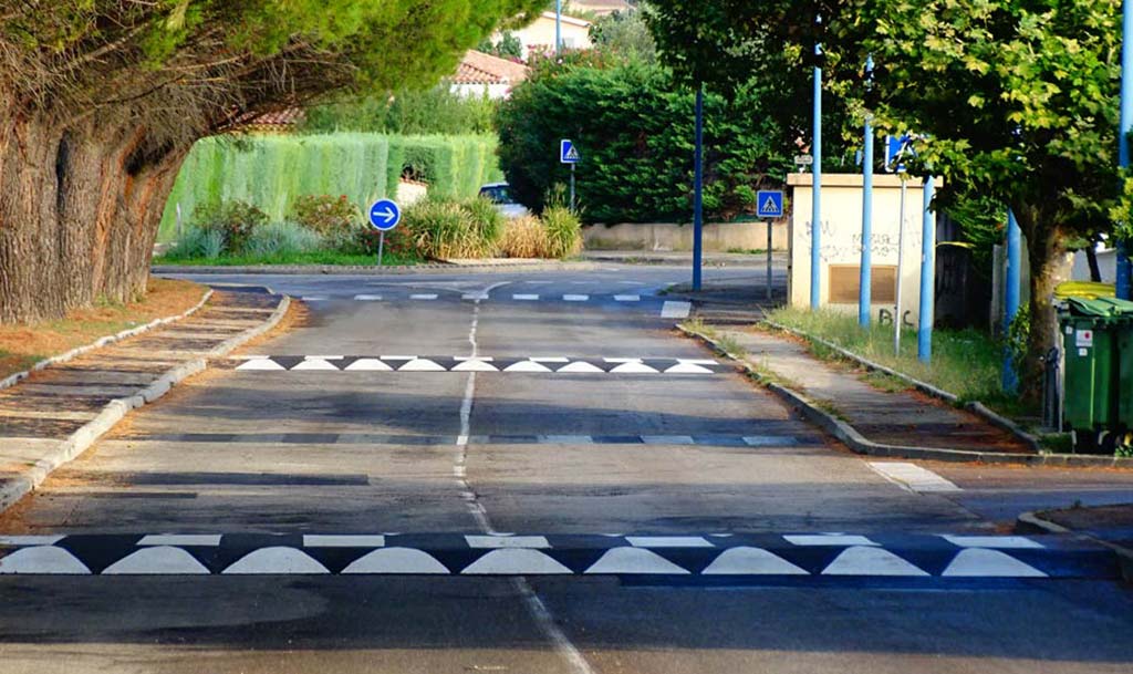 Black and white speed bumps made of asphalt on a road to calm traffic