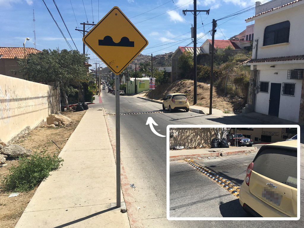 A yellow sign post to remind people there are speed bumps installed near the post