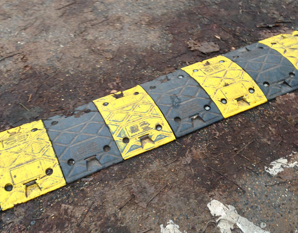 A black and yellow speed bump installed on road to calm traffic
