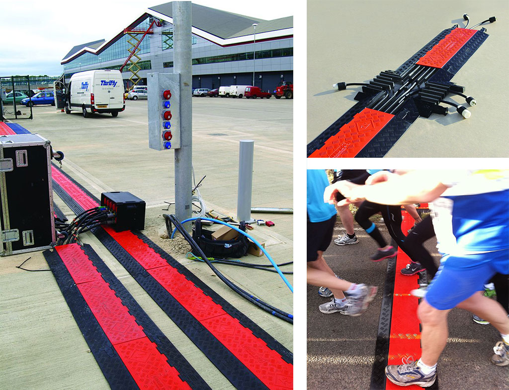 Many black and red cable protectors are connected to a long distance to cover cables in an event.