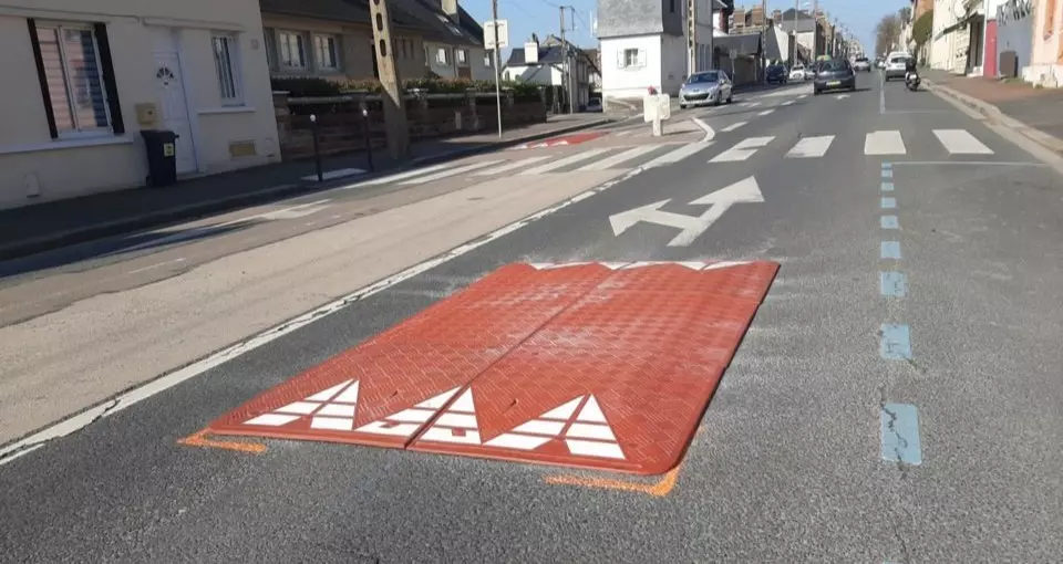 A red rubber speed cushion is mounted near the crosswalks for traffic calming.