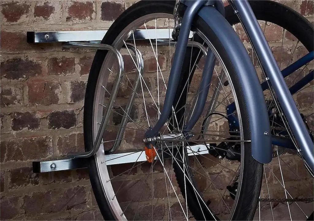 A bike is parked on a steel wall-mounted bike rack.