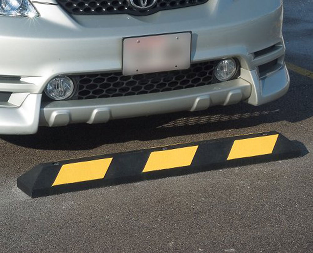 A black car stop pasted with yellow reflective tapes used for car park management