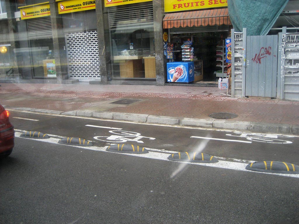 Black lane separators with yellow stripes installed on the street with white road markings to indicate cycle lanes