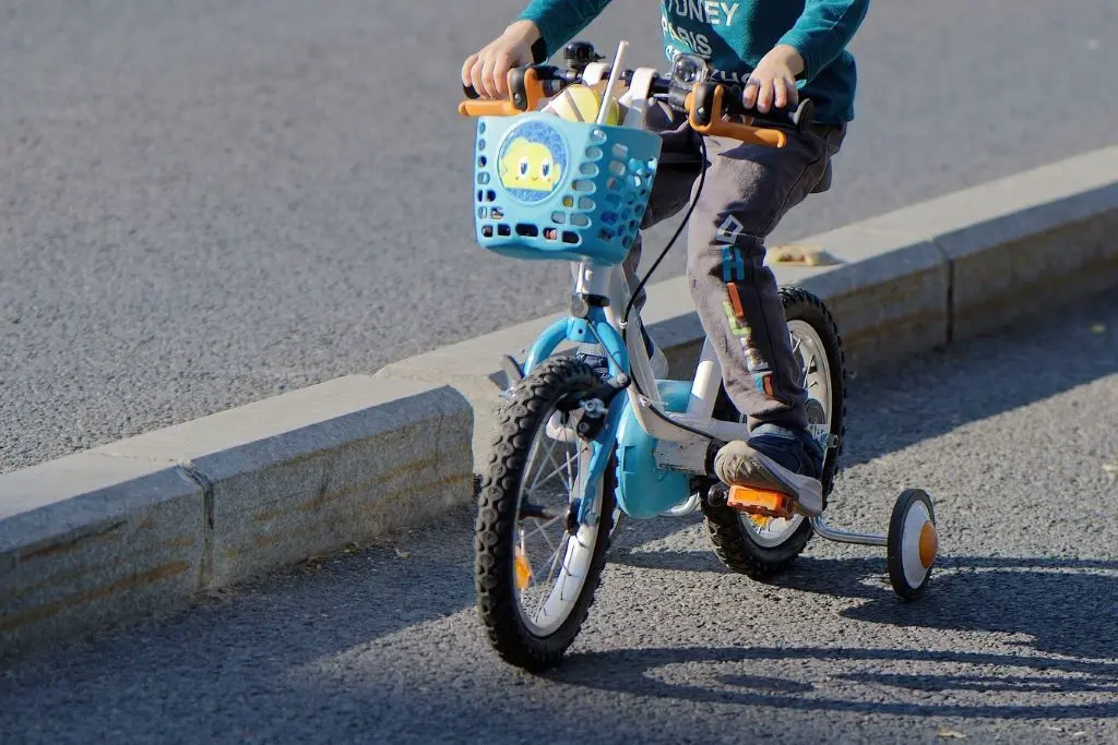 A child is riding a bike next to the concrete lane dividers on the road.