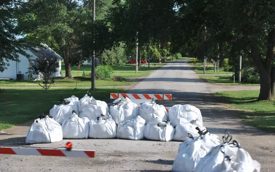 Plenty of white sandbags are put together to prevent the road sign from falling down.
