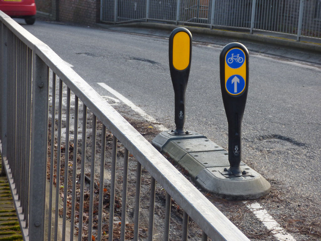 Wide lane dividers with black and yellow signposts to indicate cycle lanes to reduce traffic accidents