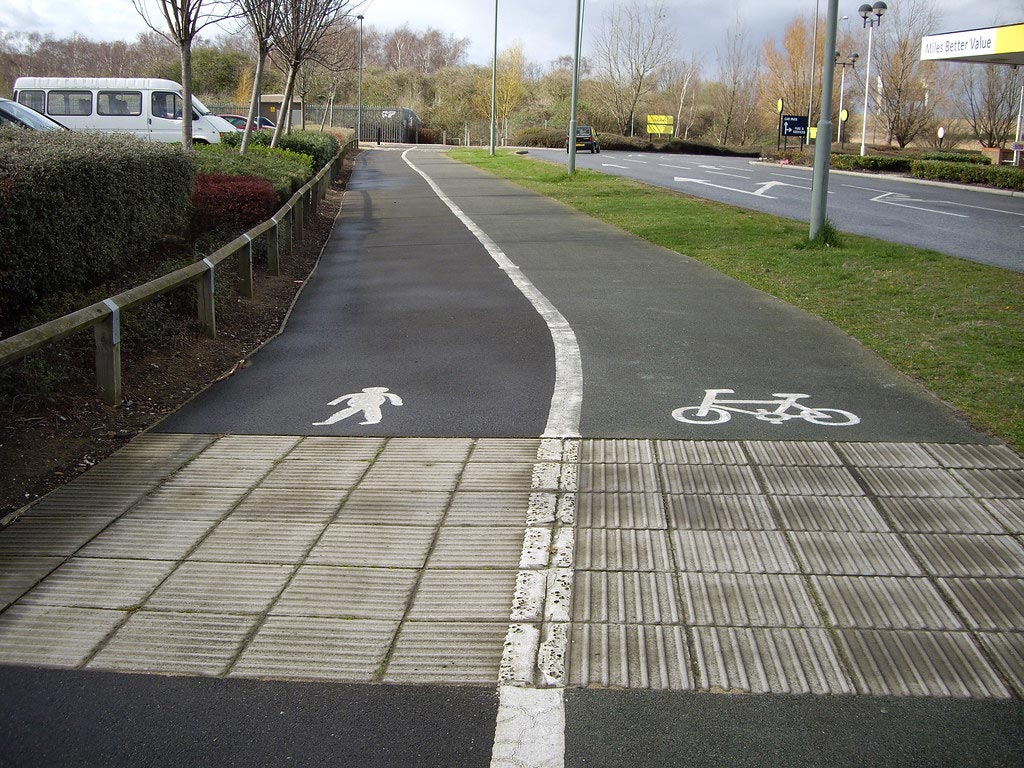 White road markings are painted on the road to separate walking lanes and cycle lanes