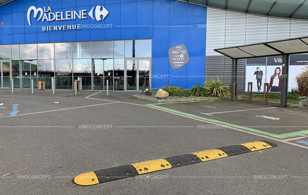 A long speed bump coloured in yellow and black installed at the entrance of a mall