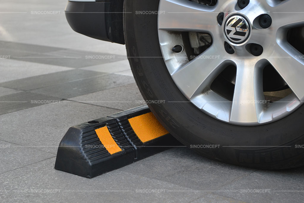 A black parking curb with yellow reflective films to stop car movement
