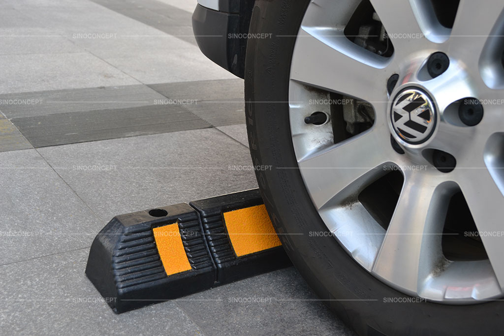 A black parking kerb with yellow reflective tapes used to stop wheels