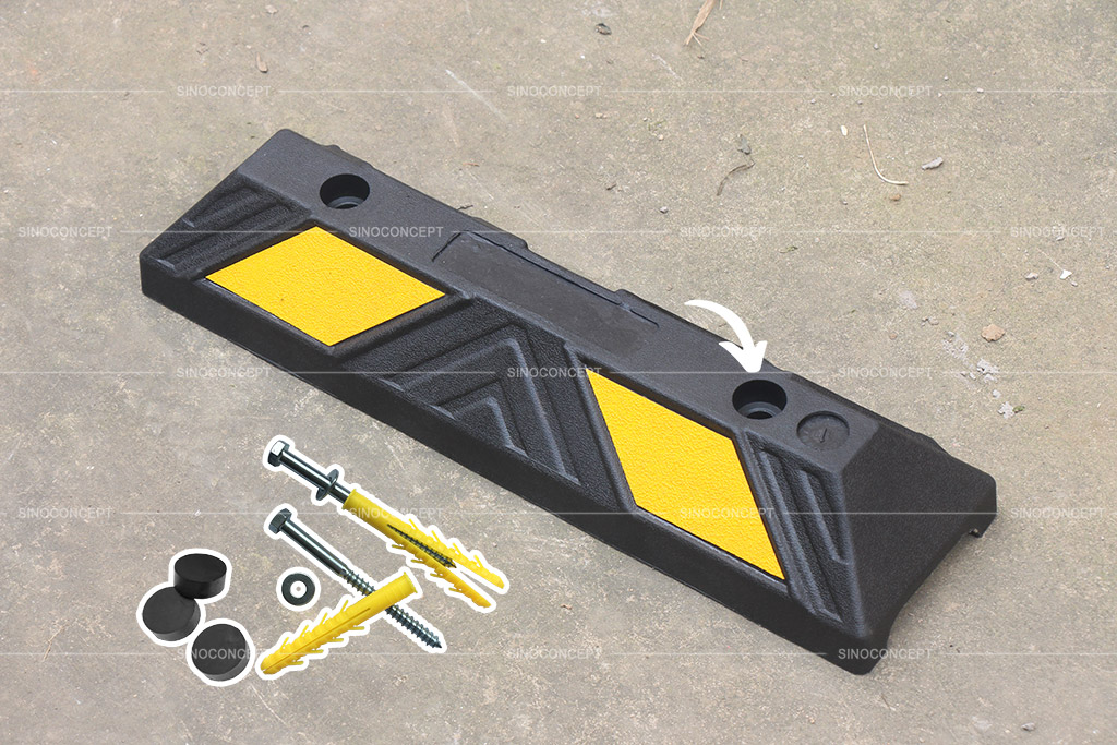 A black and yellow parking stop together with the accessories used to install the wheel stop onto the ground