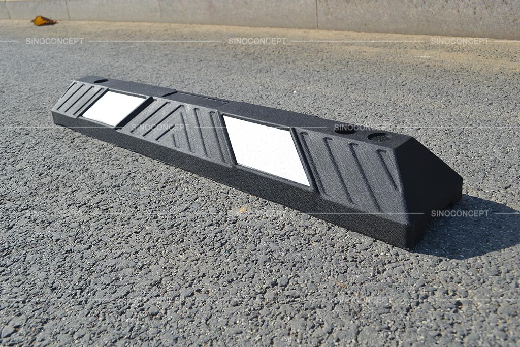 A black parking wheel stop pasted with white reflective films for car parking management