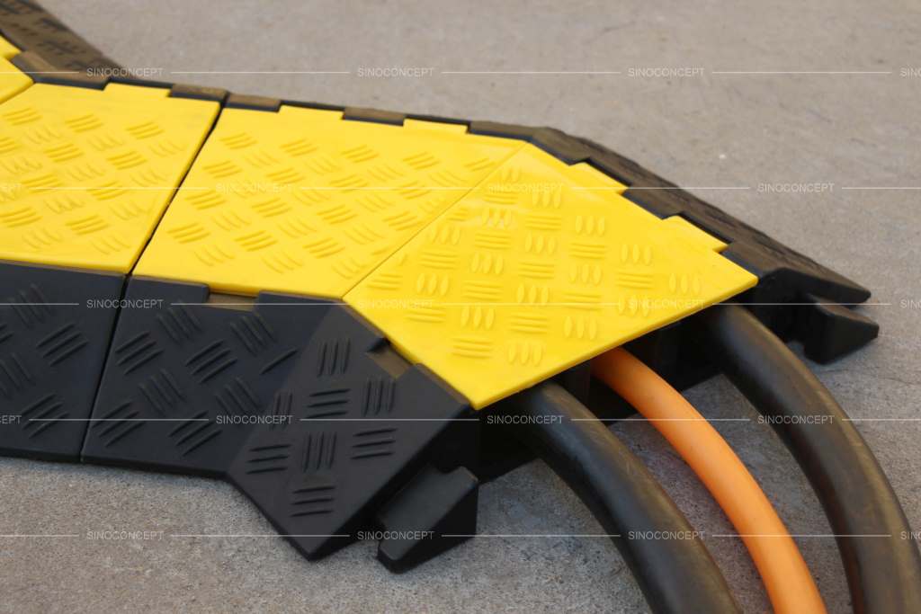 A black rubber cable protector or cable ramp with yellow lids to hide electrical cords and reduce trip hazards.