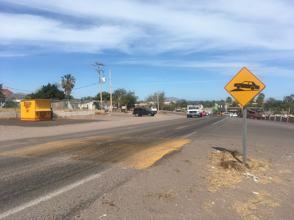 Yellow traffic sign post installed along the road to remind the drivers of the existence of speed humps